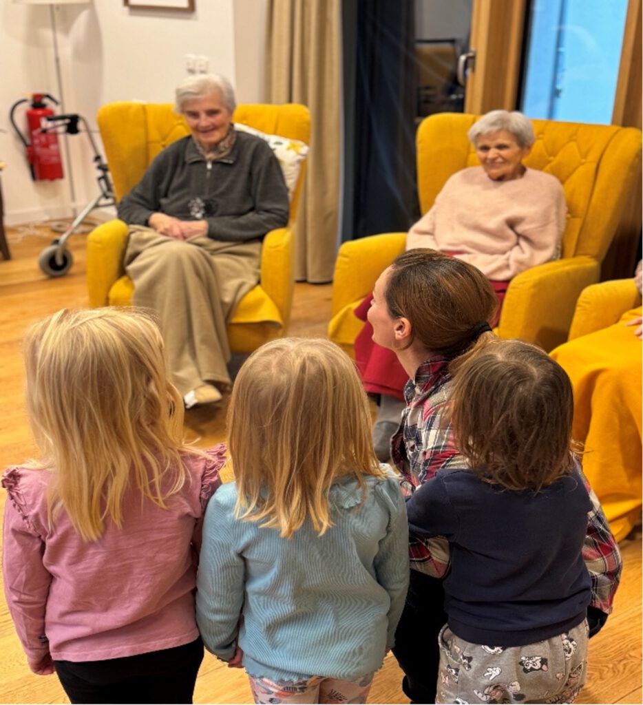 Kindergartenkinder, eine Erzieherin und mehrere ältere Damen